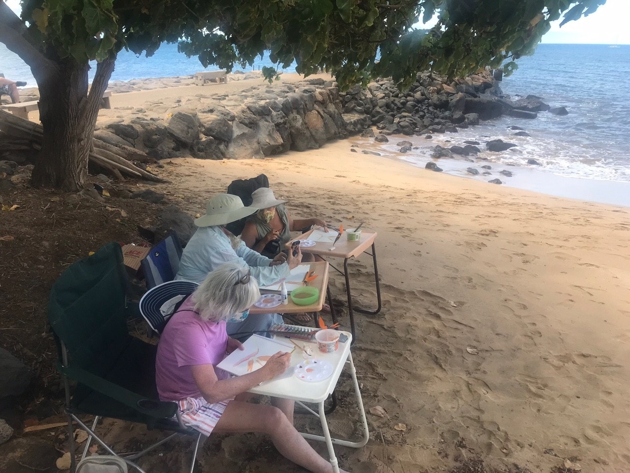 Adult students painting tropical heliconia watercolors at an outdoor class at Steinberg Art School